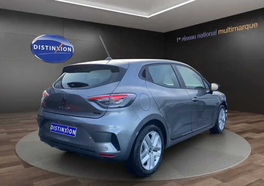 Vue 3/4 arrière droite d'une Renault Clio V gris schiste avec feux LED et jantes alliage dans un showroom.