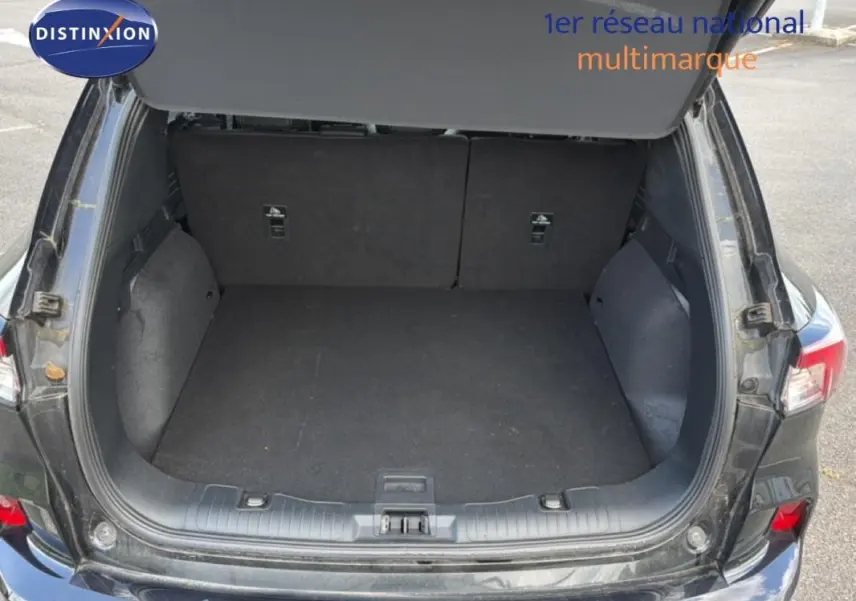 Coffre ouvert vu de l'arrière d'un Ford Kuga noir 2024, montrant un espace de chargement vide et propre.