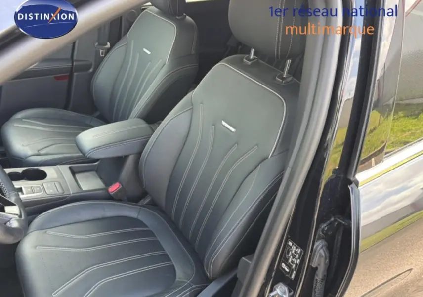 Vue intérieure côté conducteur du Ford Kuga noir 2024, sièges sport en cuir avec accoudoir central et coutures apparentes.