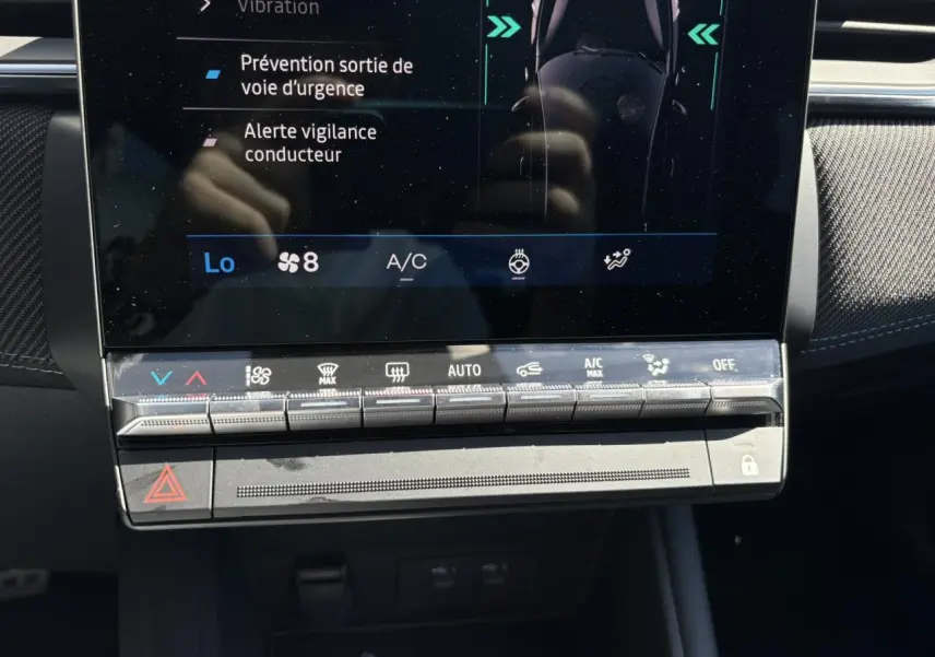 Gros plan sur la console centrale tactile du Renault Symbioz 2025 avec commandes climatisation et alertes sécurité affichées