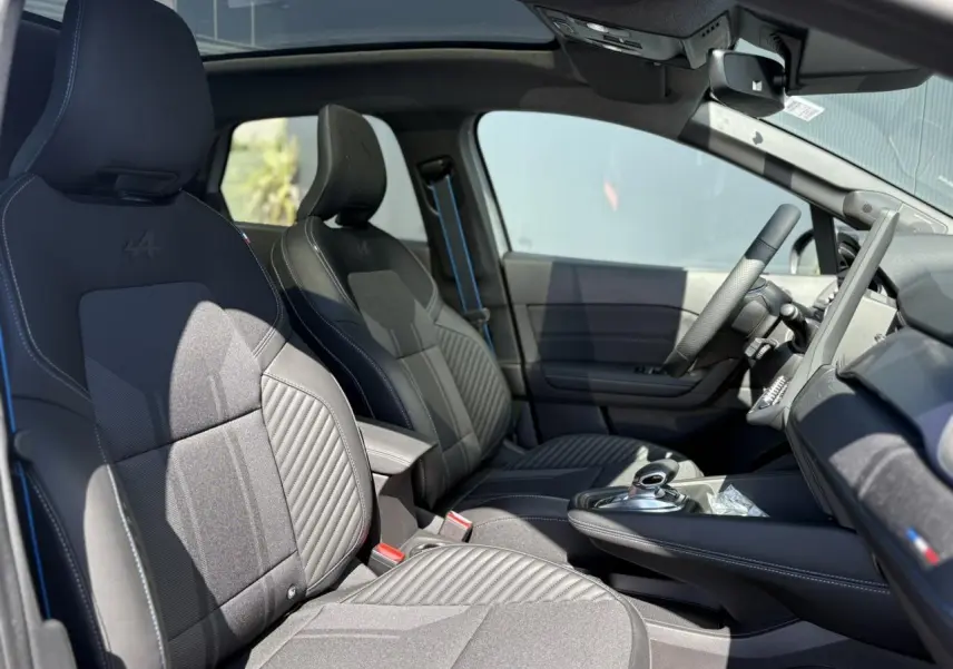 Vue intérieure côté conducteur du Renault SYMBIOZ 2025, sièges noirs avec surpiqûres bleues et toit panoramique Solarbay.