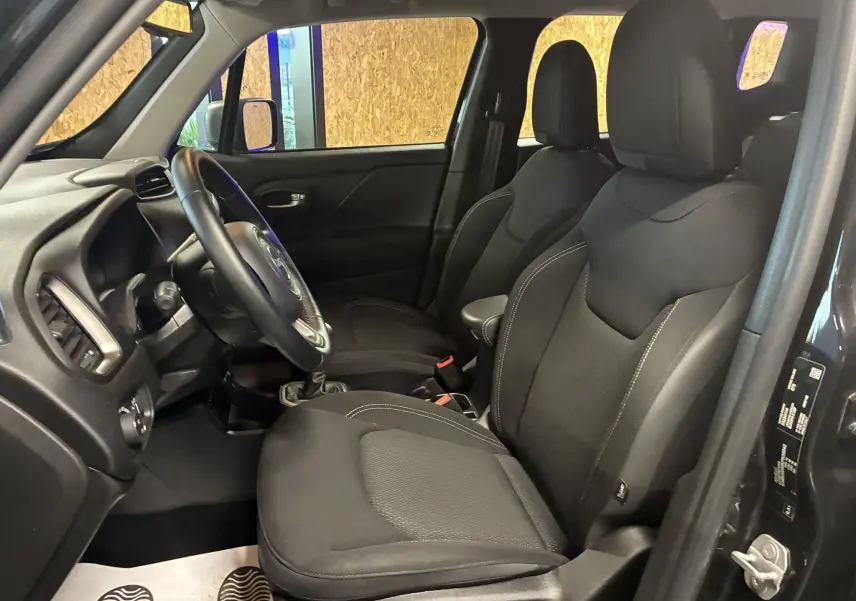 Vue intérieure côté conducteur du Jeep Renegade noir 2019, montrant les sièges avant en tissu noir et le volant.