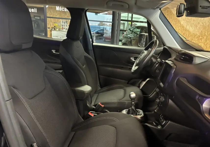 Intérieur noir du Jeep Renegade 2019, vue côté conducteur montrant sièges, volant et levier de vitesse manuel.