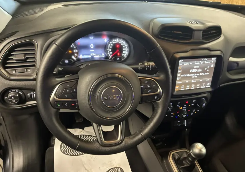 Vue intérieure centrée sur le volant noir du Jeep Renegade 2019 avec tableau de bord et écran tactile allumés.