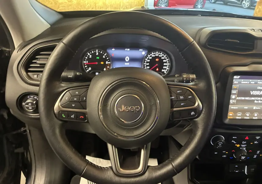 Vue intérieure centrée sur le volant en cuir noir du Jeep Renegade 2019 avec tableau de bord et écran tactile visible.