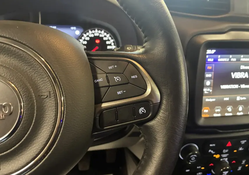 Gros plan sur le volant noir du Jeep Renegade 2019 avec commandes de régulateur de vitesse et tableau de bord lumineux.