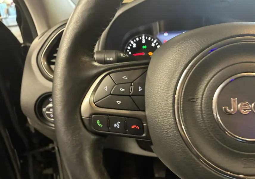 Gros plan sur le volant noir du Jeep Renegade 2019, avec commandes intégrées et tableau de bord en arrière-plan.