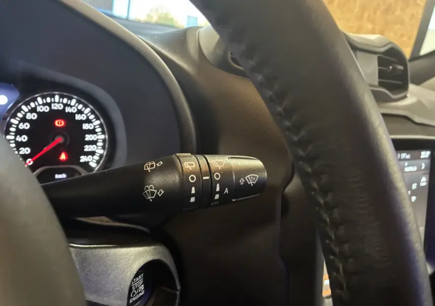 Gros plan sur la manette d'essuie-glace à gauche du volant noir du Jeep Renegade 2019, tableau de bord en arrière-plan.