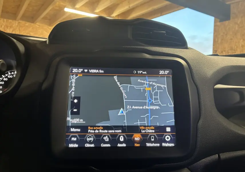 Écran tactile GPS allumé au tableau de bord du Jeep Renegade noir, avec commandes climatisation visibles.