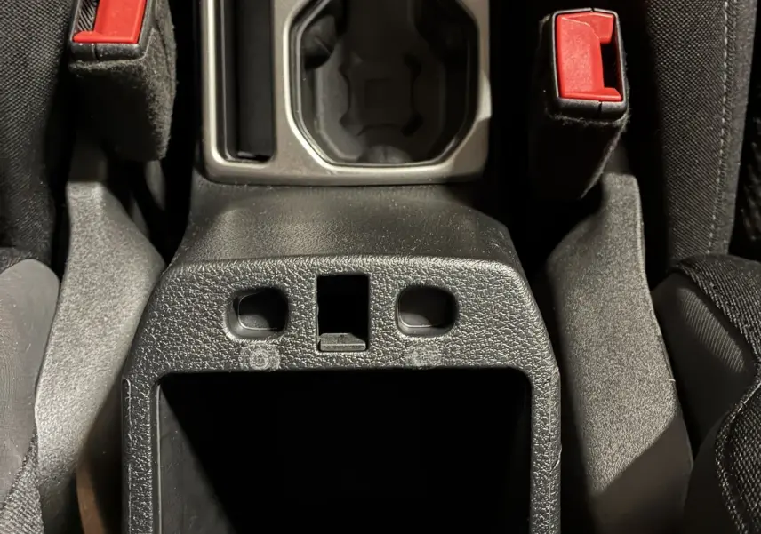 Gros plan sur la console centrale noire du Jeep Renegade 2019, montrant les ceintures de sécurité rouges et les porte-gobelets.