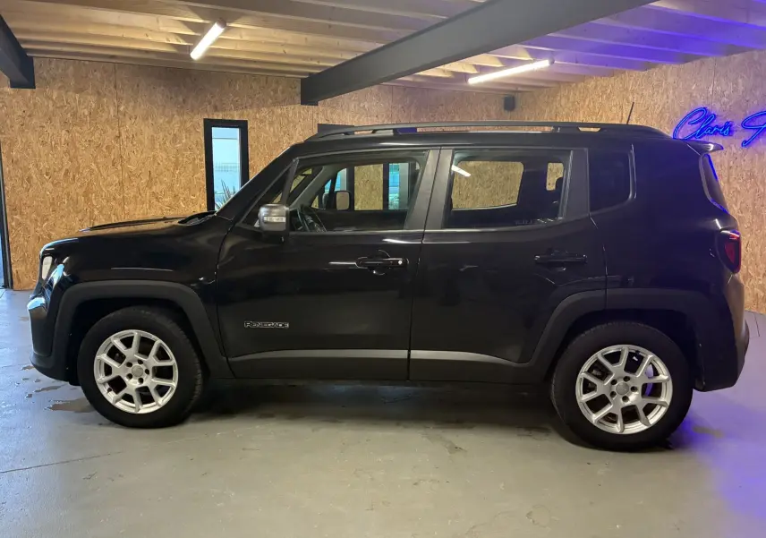 Profil côté gauche d'un Jeep Renegade noir 2019 avec jantes argentées dans un garage éclairé au néon.