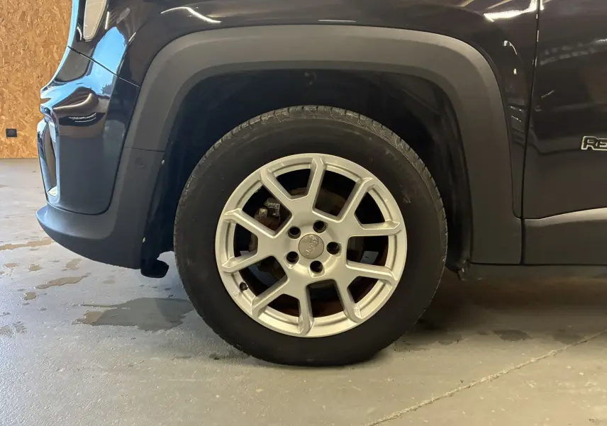 Gros plan sur la roue avant gauche d’un Jeep Renegade noir 2019 avec jante argentée et logo Jeep au centre.