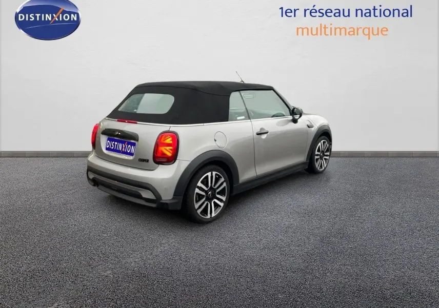 Vue 3/4 arrière droite d'une MINI Cabriolet 2023 Melting Silver avec toit noir et feux arrière à motif Union Jack.