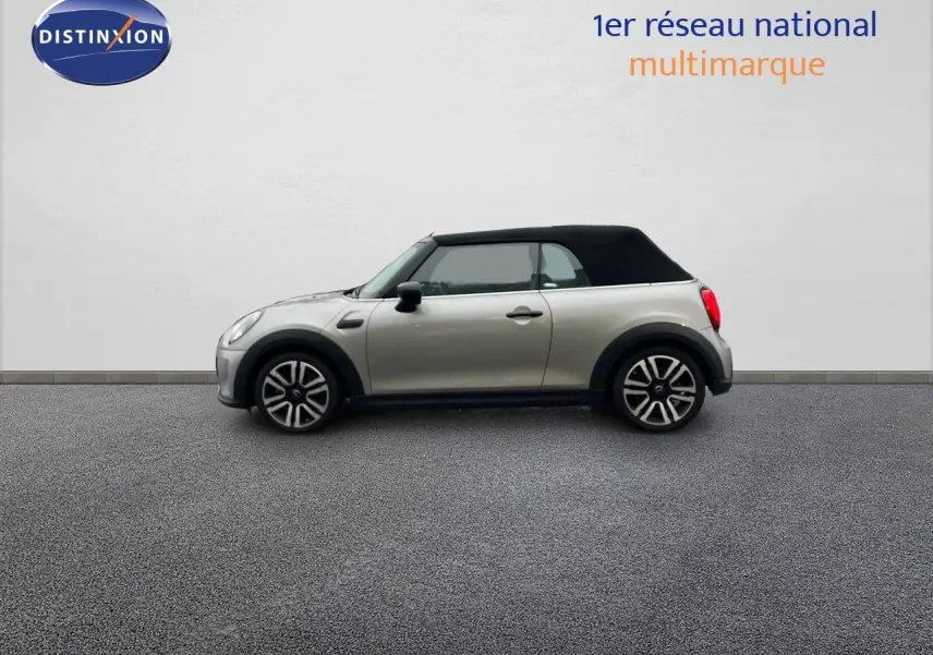 Profil gauche d'une MINI Cabriolet 2023 couleur Melting Silver avec capote noire fermée sur fond neutre.