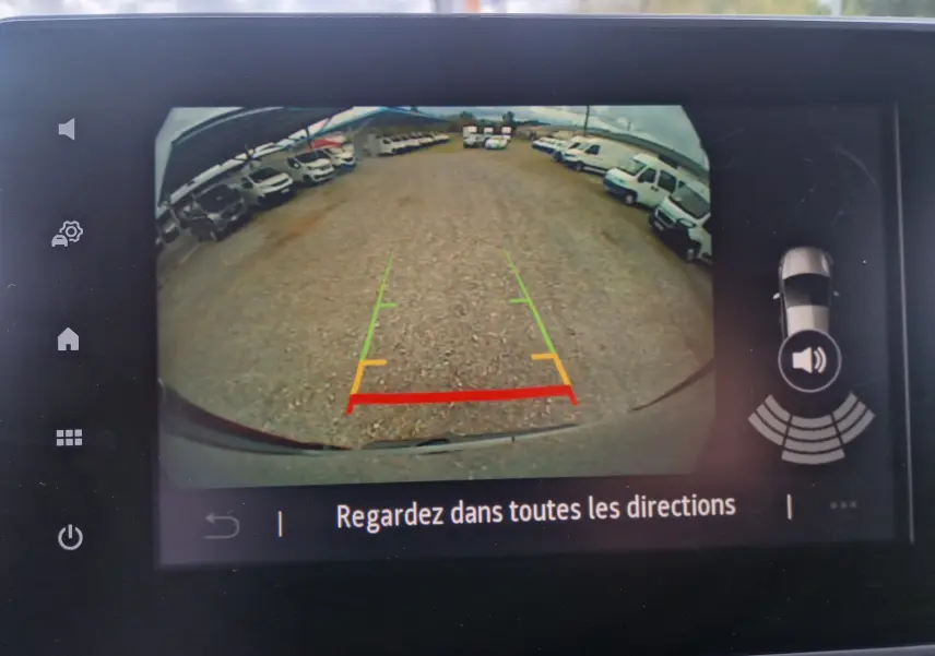 Affichage de la caméra de recul du Renault Trafic Fourgon gris urbain, montrant l'arrière et le parking avec plusieurs véhicules blancs.