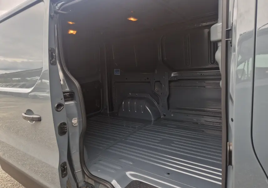 Vue intérieure du coffre arrière ouvert du Renault Trafic Fourgon gris urbain L1H1 2025, montrant l'espace de chargement vide.