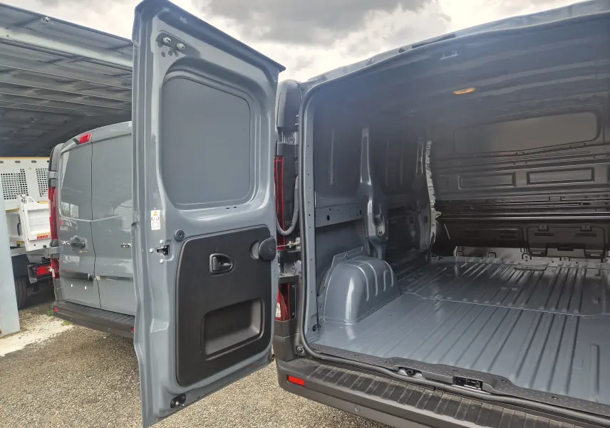 Vue arrière ouverte du Renault Trafic Fourgon L1H1 2025 gris urbain, montrant l'espace de chargement vide et les portes battantes.