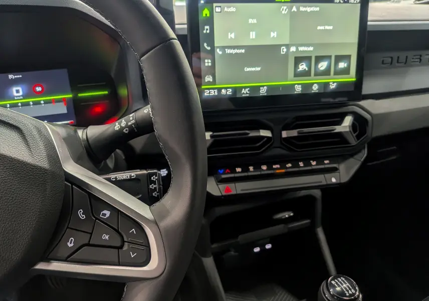 Vue rapprochée de l'intérieur du Dacia Duster gris Schiste 2025, montrant le volant, la boîte manuelle et l'écran tactile central.