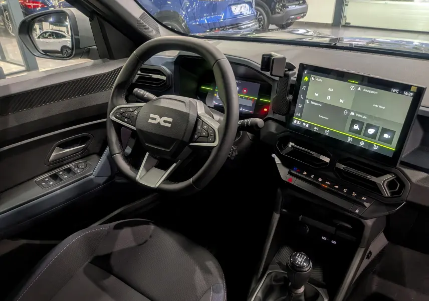 Intérieur du Dacia Duster 2025 avec vue sur le volant multifonction, écran tactile et levier de vitesse manuel.