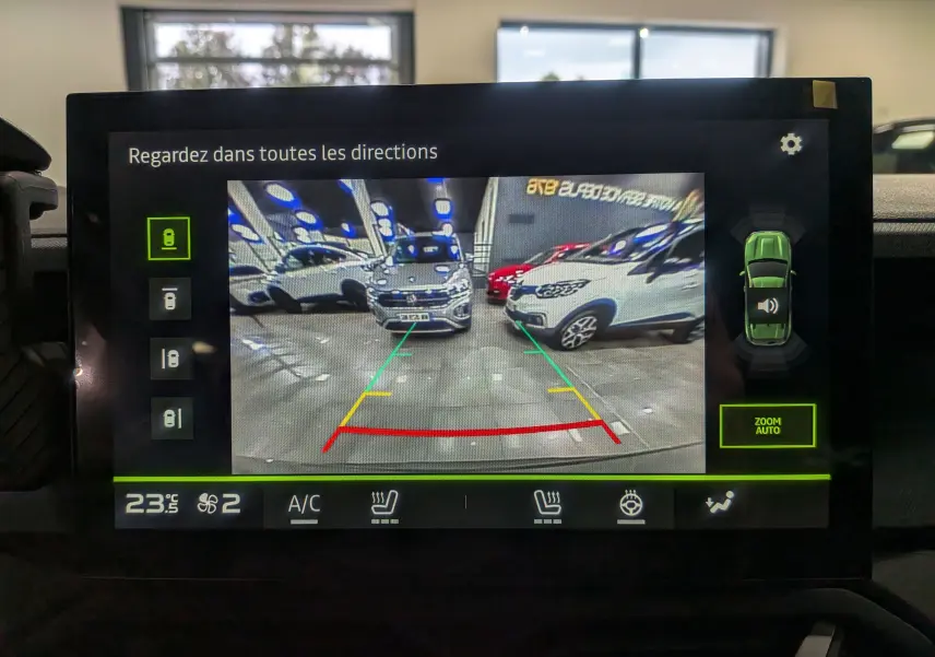 Écran de caméra de recul montrant un Dacia Duster gris schiste en vue arrière dans un garage lumineux.