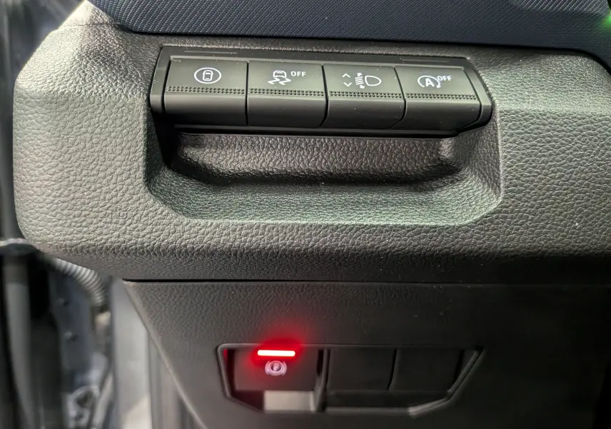 Gros plan sur les commandes de sécurité et d'assistance du tableau de bord du Dacia Duster 2025 en tissu noir.