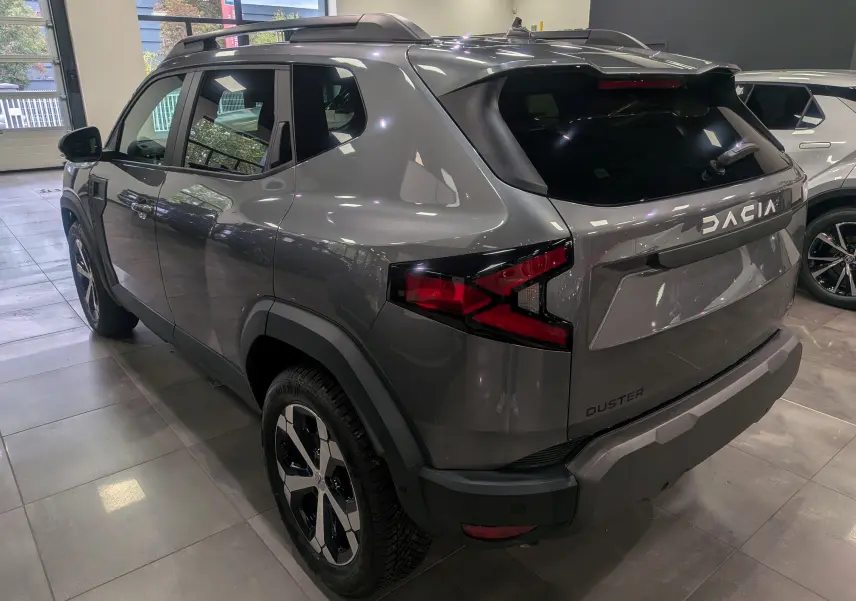 Vue 3/4 arrière droite du Dacia Duster gris schiste 2025 avec jantes bi-ton et feux arrière LED distinctifs.