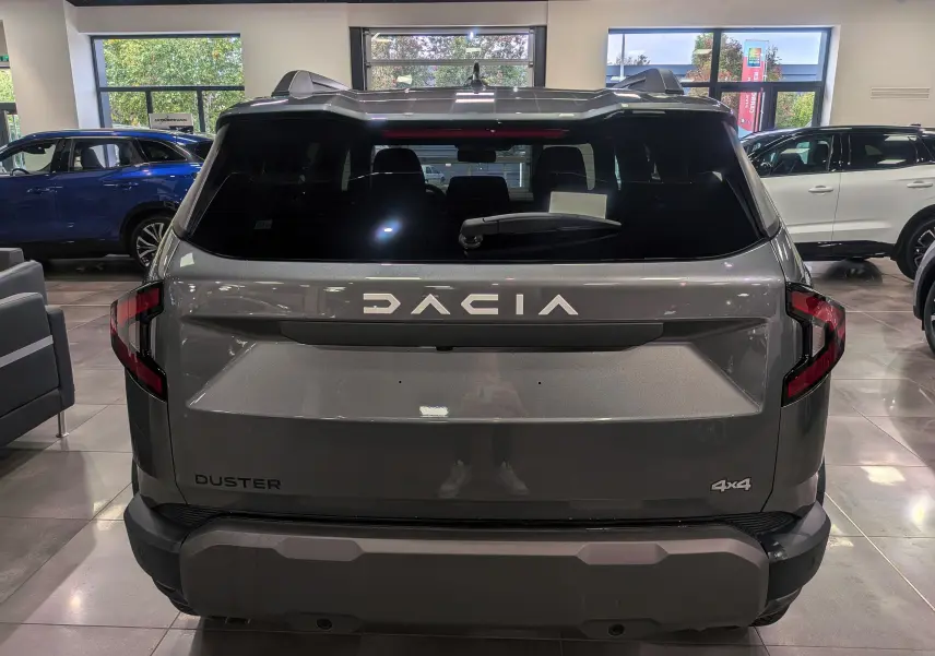 Vue arrière du Dacia Duster gris schiste 2025 avec logo DACIA et badge 4x4 visible en showroom.