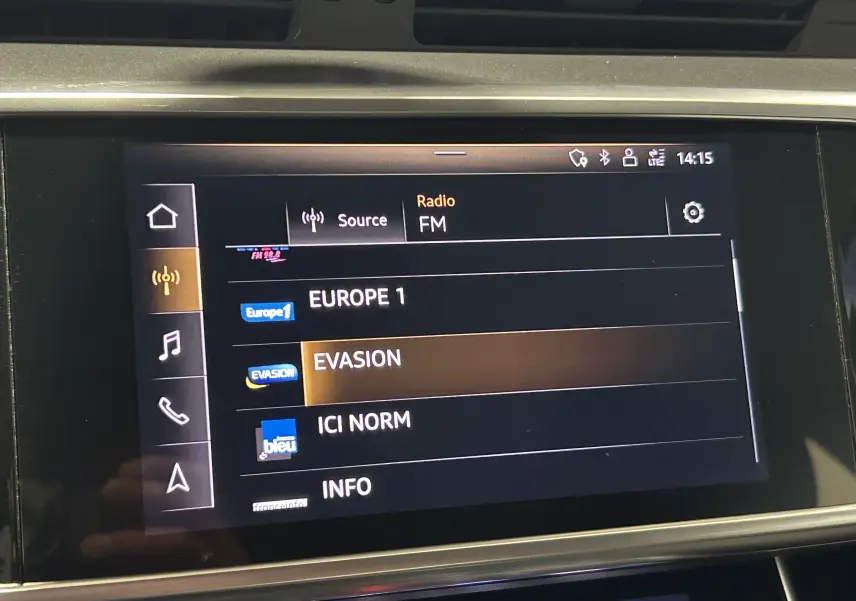 Écran tactile central de l'Audi A6 Avant noir 2019 affichant les stations radio FM avec sélection sur EVASION.