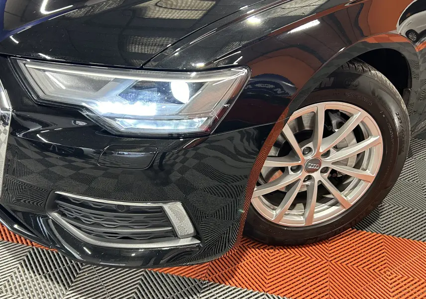 Gros plan sur l'avant droit noir d'une Audi A6 Avant 40 TDI 2019 avec phare LED allumé et jante alu multi-branches.