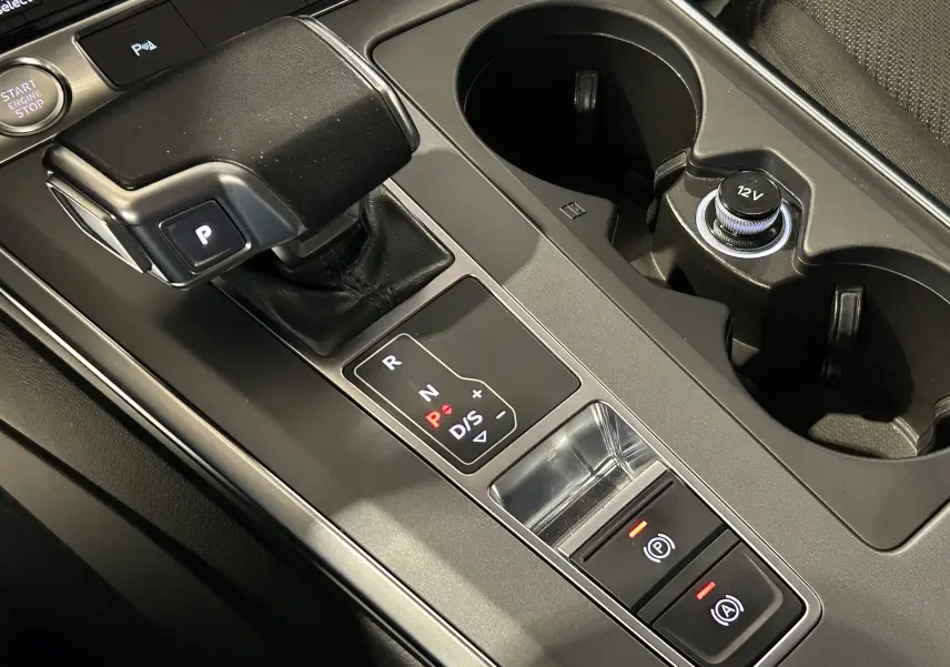 Vue rapprochée de la console centrale noire de l'Audi A6 Avant 40 TDI 2019, avec levier de vitesse automatique et prises 12V.