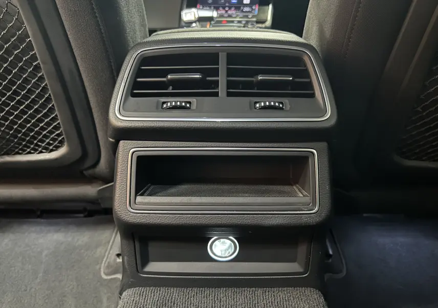 Détail de la console arrière noire avec bouches d'aération et prise allume-cigare dans une Audi A6 Avant 2019.