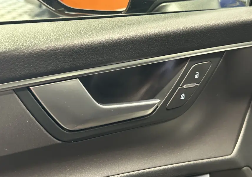 Poignée de porte intérieure côté gauche en plastique noir et métal brossé d'une Audi A6 Avant noire 2019.