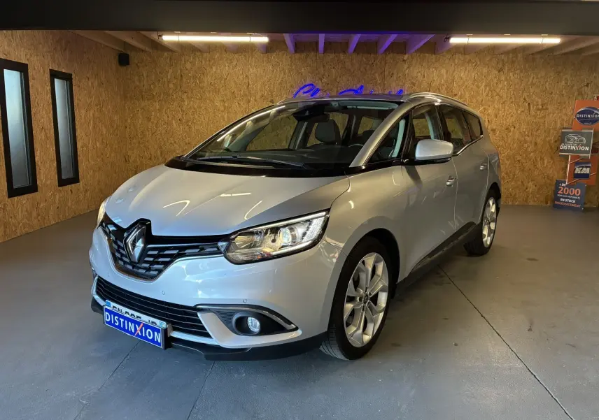 Renault Grand Scenic gris vue 3/4 avant droit dans un garage avec éclairage intérieur et plaques Distinxion.