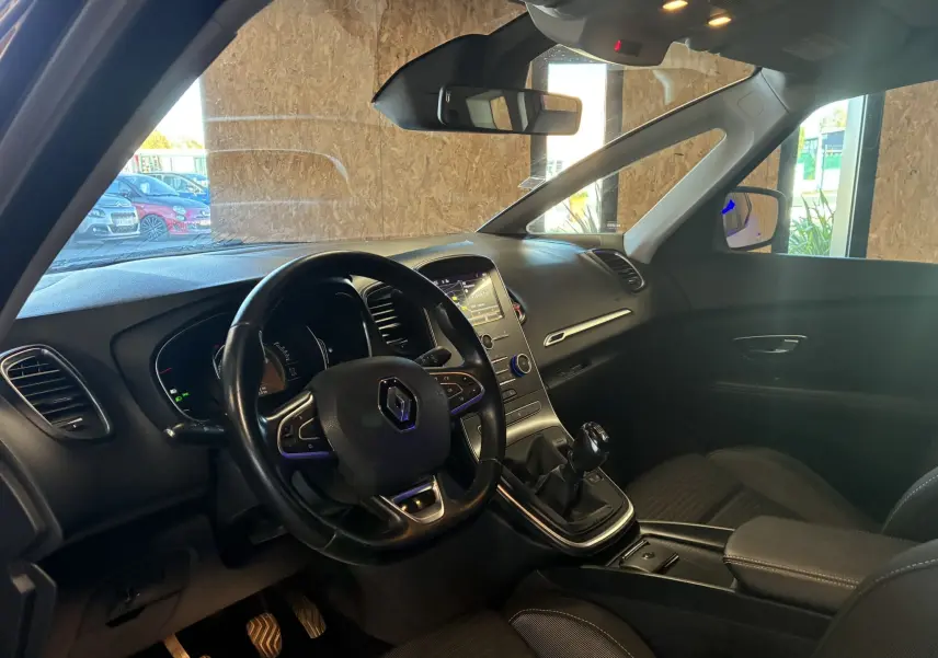 Intérieur noir du Renault Grand Scenic 1.5 DCI 110 Business vu côté conducteur, avec tableau de bord et levier manuel visibles.