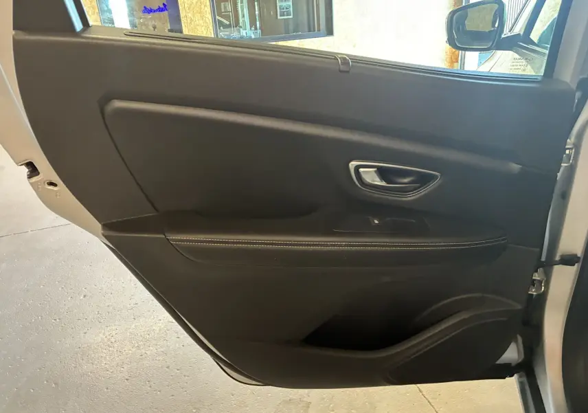 Porte avant gauche ouverte du Renault Grand Scenic gris 2017, intérieur noir avec poignée argentée et surpiqûres blanches.