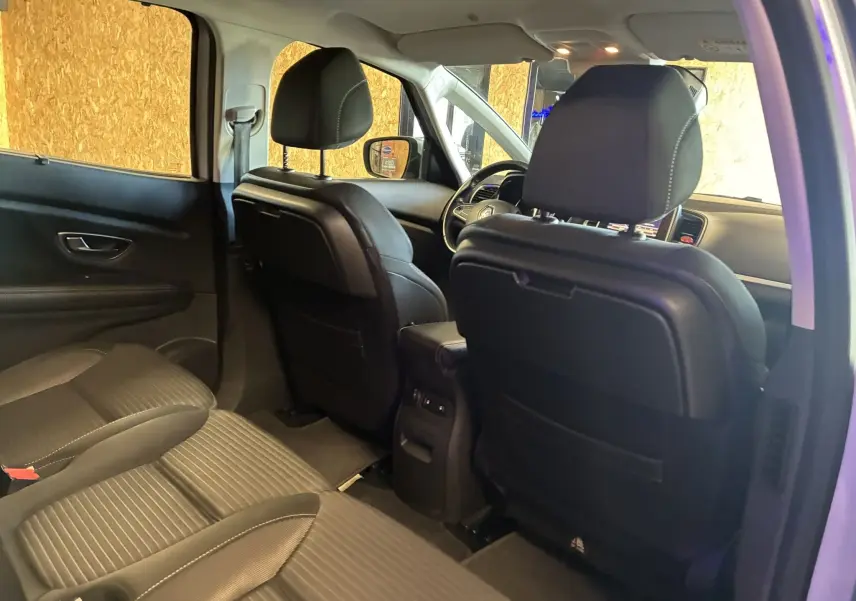 Vue intérieure arrière du Renault Grand Scenic 2017 avec sièges noirs en cuir et tissu, mettant en valeur l'espace et le confort.