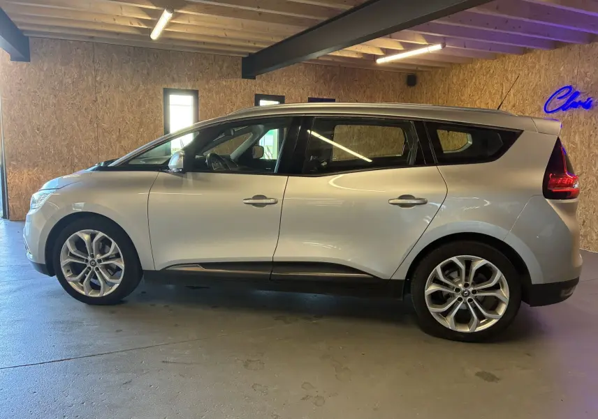 Profil côté gauche d'un Renault Grand Scenic gris 2017, montrant ses lignes fluides et ses feux arrière caractéristiques.