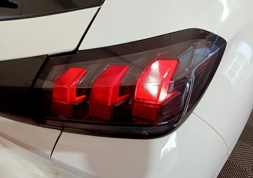 Gros plan sur le feu arrière droit rouge de la Peugeot 208 blanche, version 1.5 BlueHDi 100 S&S Premium 2022.