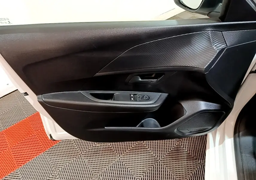 Vue intérieure côté gauche de la porte avant blanche de la Peugeot 208 1.5 BlueHDi avec commandes de vitres et miroir.
