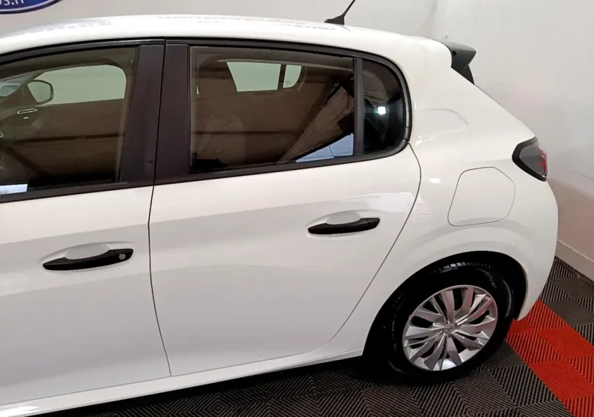 Vue latérale côté droit d'une Peugeot 208 blanche de 2022, mettant en valeur les portes arrière et la roue arrière.