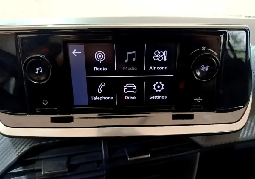 Écran tactile central noir affichant les options radio, média, climatisation, téléphone, conduite et réglages dans une Peugeot 208.