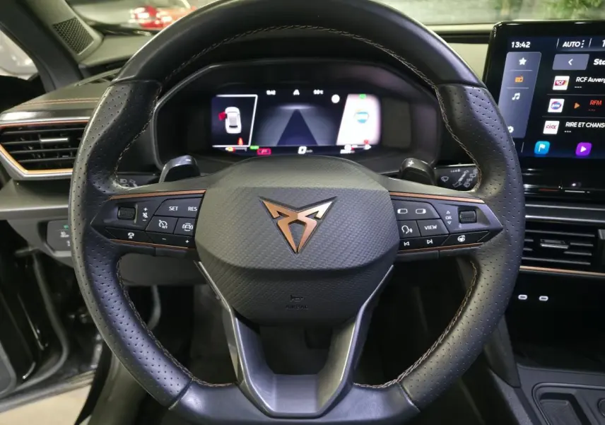 Vue rapprochée du volant sport noir avec logo cuivre et tableau de bord digital du CUPRA Formentor 1.4 e-Hybrid 2023.