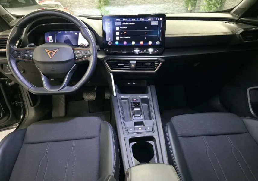 Vue intérieure avant du CUPRA Formentor 1.4 e-Hybrid 2023, tableau de bord noir avec écran tactile central et volant sport cuir.