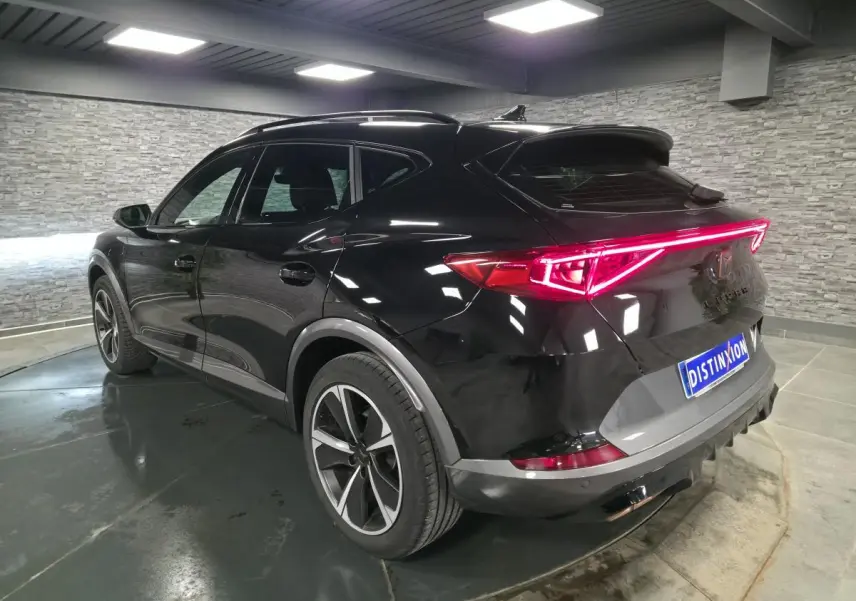 Vue 3/4 arrière droite du CUPRA Formentor noir Minuit avec bandeau LED arrière Infinite Light allumé.