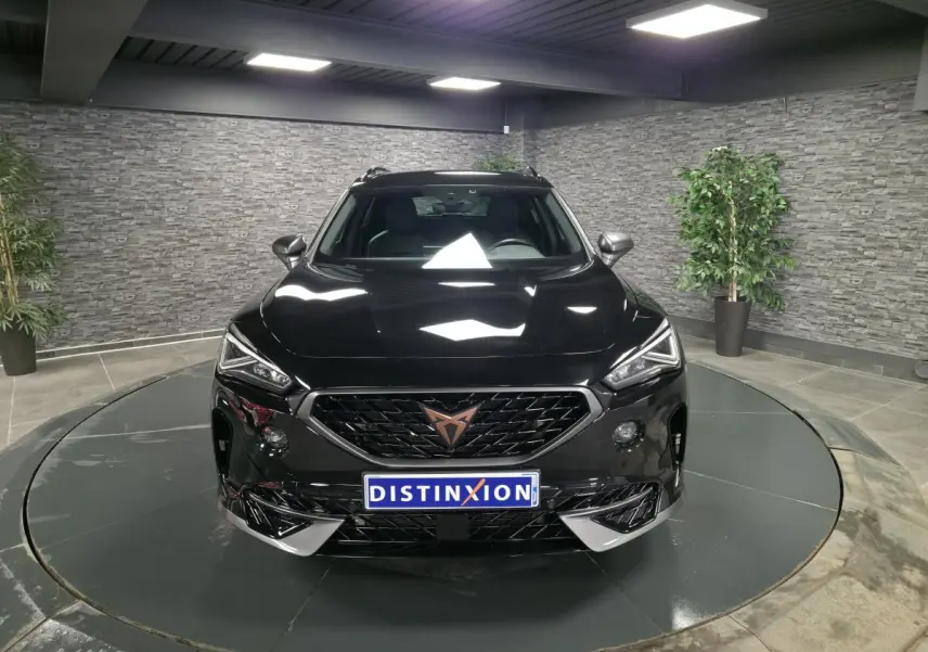 Vue avant d'une CUPRA Formentor noire avec calandre marquée et logo cuivre dans un showroom.
