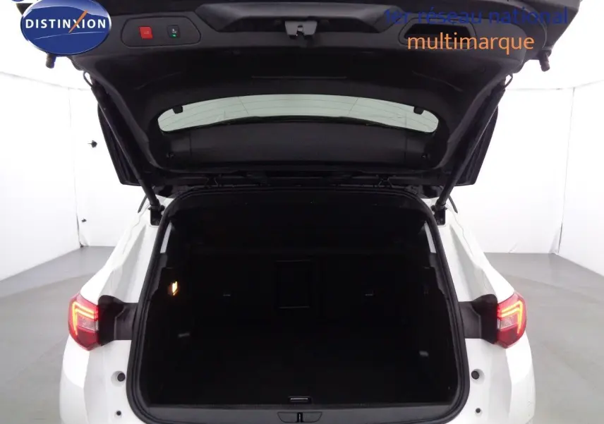 Vue arrière du coffre ouvert d'un Opel Grandland X blanc nacré, avec feux arrière allumés dans un studio lumineux.