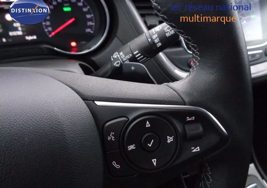 Gros plan sur le volant en cuir noir de l'Opel Grandland X 1.6 Hybrid Turbo 300, avec commandes intégrées visibles.