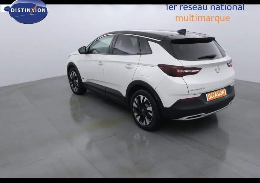 Opel Grandland X blanc nacré métal vu en 3/4 arrière droit, toit noir contrasté et jantes noires distinctives.