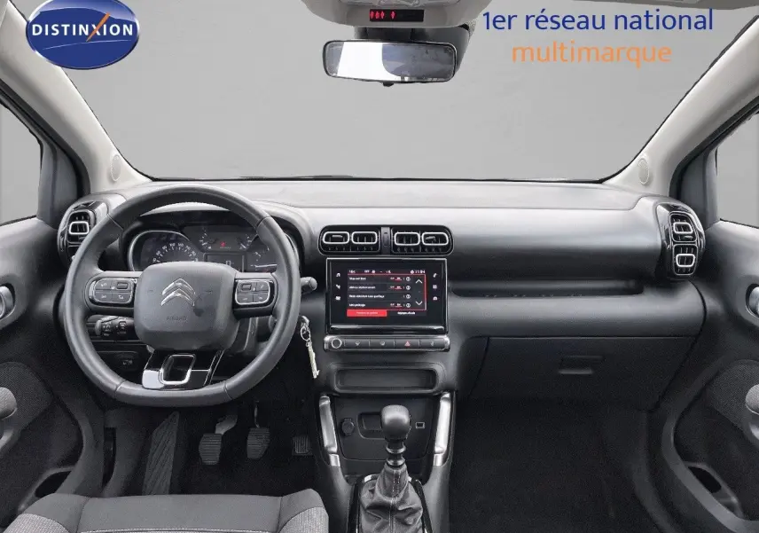 Tableau de bord et volant noir de la Citroën C3 Aircross 2023 vus de face, avec écran tactile central allumé.