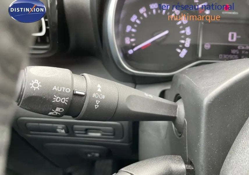 Gros plan sur la manette des feux d’un Citroën C3 Aircross blanc polaire, tableau de bord en arrière-plan flou.